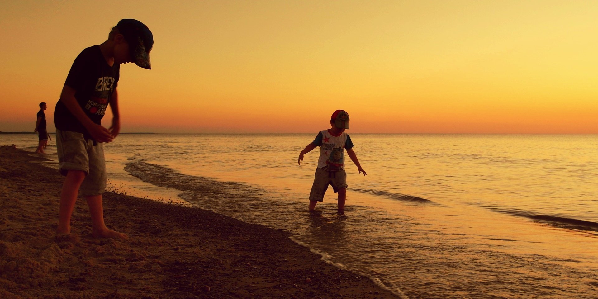 Dzieci bawiące się o zachodzie słońca na bałtyckiej plaży.