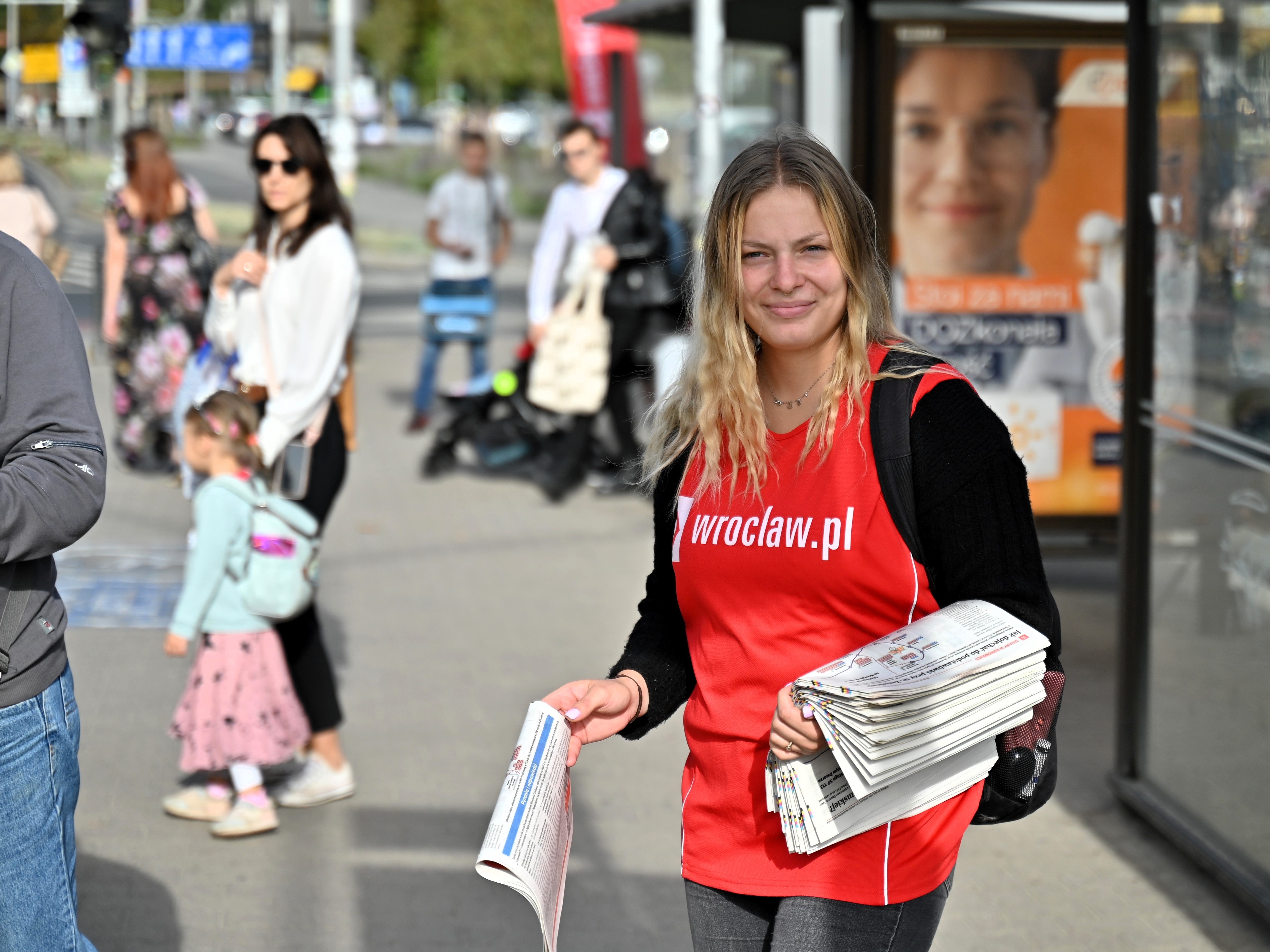 Powiększ obraz: <p>Na pl. Jana Pawła II Karolina rozdaje biuletyn wroclaw.pl zawierający informacje o zmianach w MPK.</p>