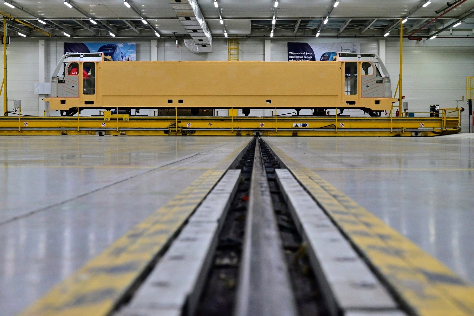 Pudło lokomotywy Traxx pod koniec etapu produkcji na hali, gdzie pracują roboty lakierujące i śrutujące