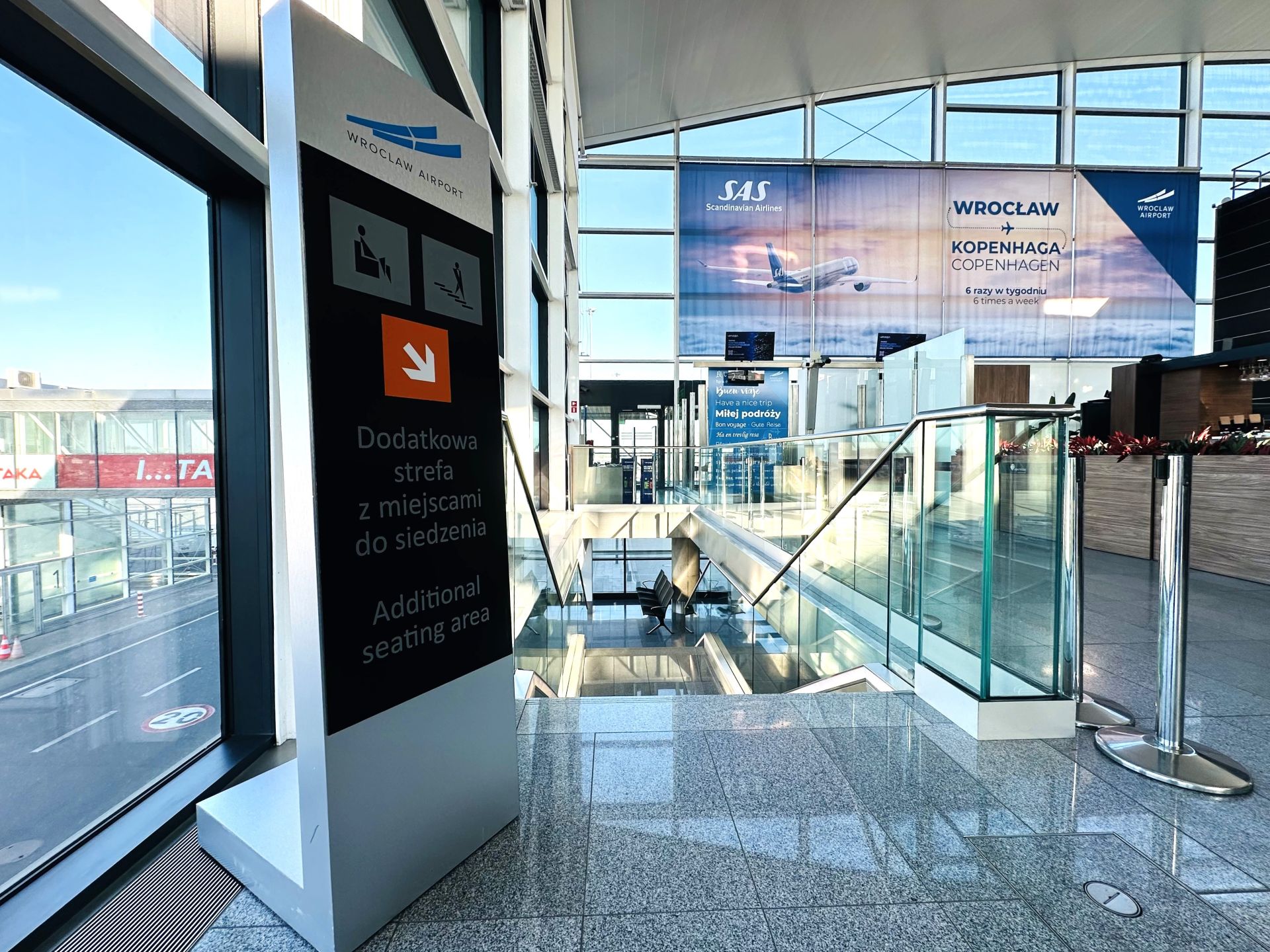 Zejście do nowo otwartej przestrzeni dla pasażerów w hali odlotów