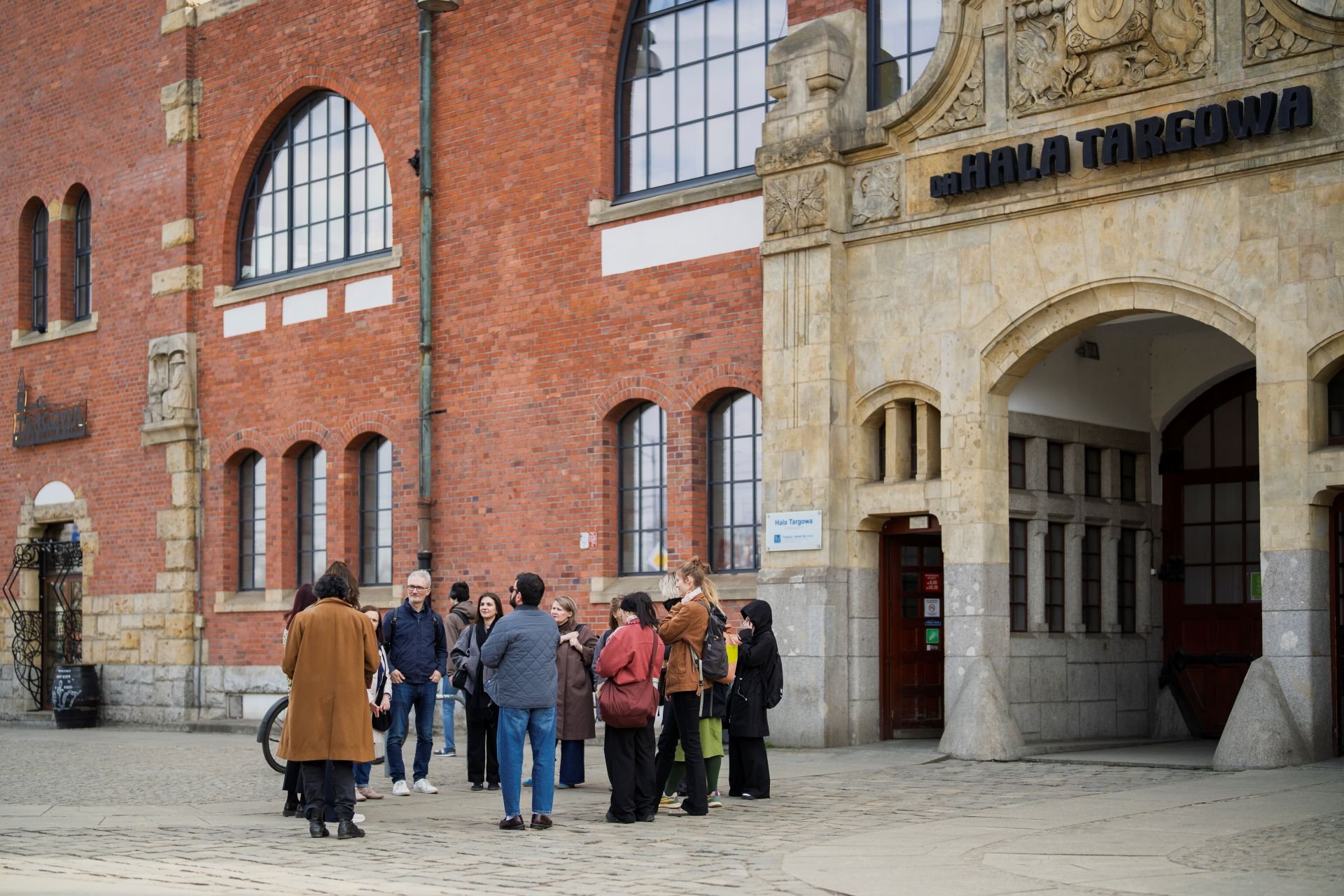 Przedstawiciele Fundacji Placemaking Europe z wizytą studyjną przed Halą Targową