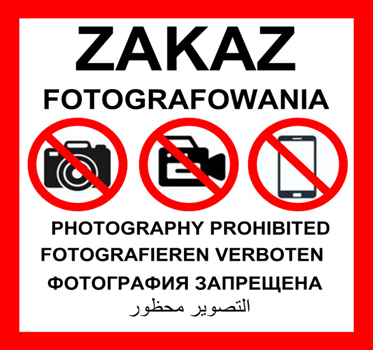 Znak zakazu fotografowania stanowi biała tablica w kształcie kwadratu o boku 60 cm, z czerwoną obwódką o szerokości 3,35 cm, z umieszczonym na górze napisem „ZAKAZ” złożonym z liter w czarnym kolorze o wysokości 7,45 cm oraz z umieszczonym pod nim napisem „FOTOGRAFOWANIA” złożonym z liter w czarnym kolorze o wysokości 3,35 cm, z umieszczonymi poniżej na środku trzema czarno-białymi rysunkami na białym tle obrazującymi aparat fotograficzny, kamerę oraz telefon komórkowy, znajdującymi się w trzech okręgach o średnicy 16 cm, z czerwoną obwódką o szerokości 1,5 cm, przekreślonymi po skosie od lewej górnej części okręgu do prawej dolnej części okręgu czerwoną linią o szerokości 1,5 cm. Pod rysunkami umieszcza się napisy w czterech językach obcych złożone z liter w czarnym kolorze o wysokości 2,24 cm, będące tłumaczeniem napisu „ZAKAZ FOTOGRAFOWANIA” na język angielski, niemiecki, rosyjski i arabski.