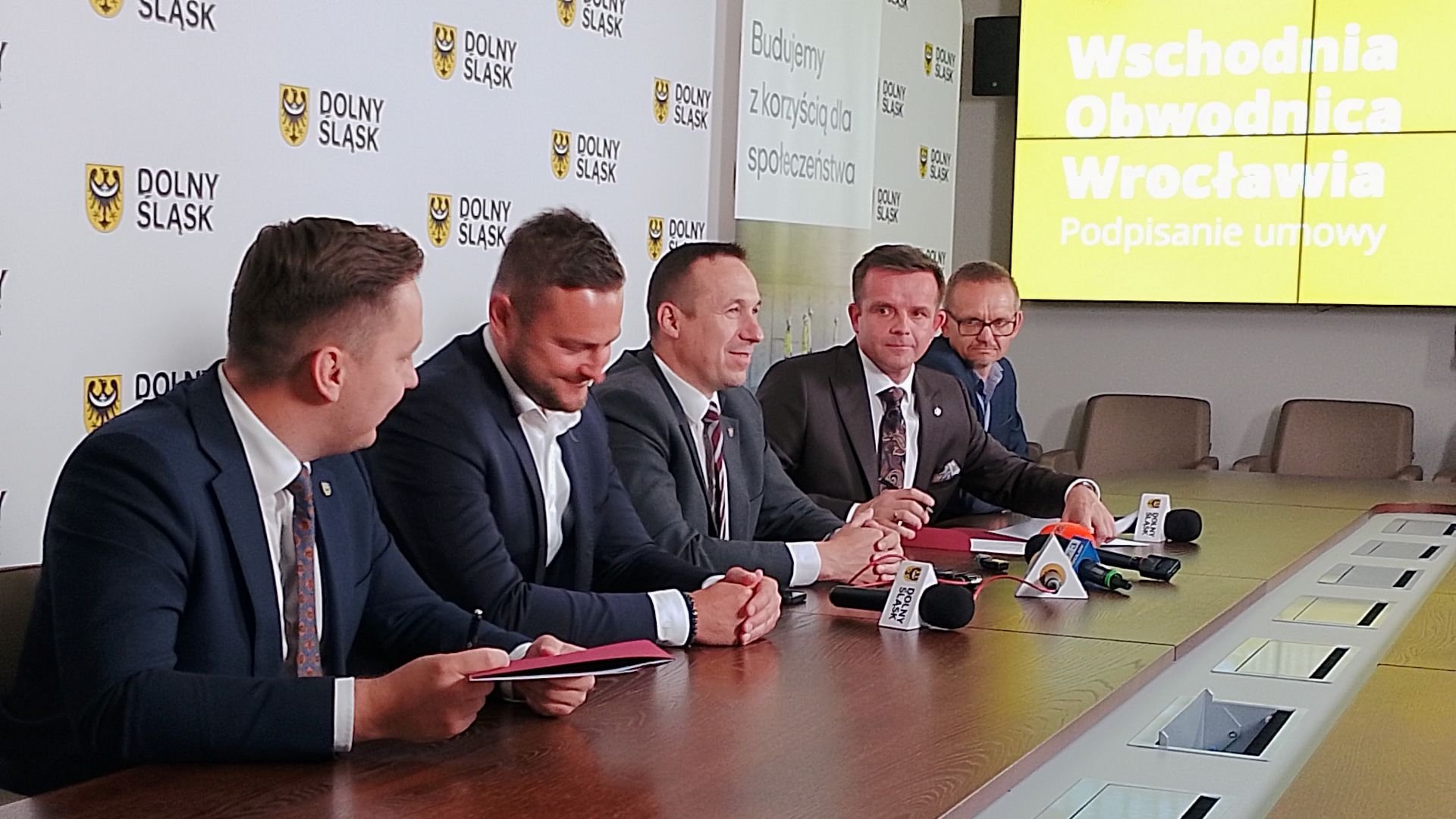 Podpisanie umowy na budowę ostatniego odcinka Wschodniej Obwodnicy Wrocławia. Przy stole dyrektor Dolnośląskiej Służby Dróg i Kolei Mateusz Masłowski, wicemarszałek Michał Rado, marszałek Paweł Gancarz, członek zarządu spółki Sanska Piotr Subczak i dyrektor kontraktu Paweł Fidelak.