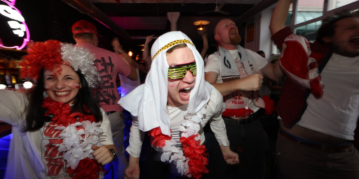 Na zdjęciu widać kibiców z Wrocławia, którzy dopingują Polaków na meczu Polska - Arabia Saudyjska w pubie Wembley. Kibice są poprzebierani w różne stroje, niektórzy w barwach biało-czerwonych