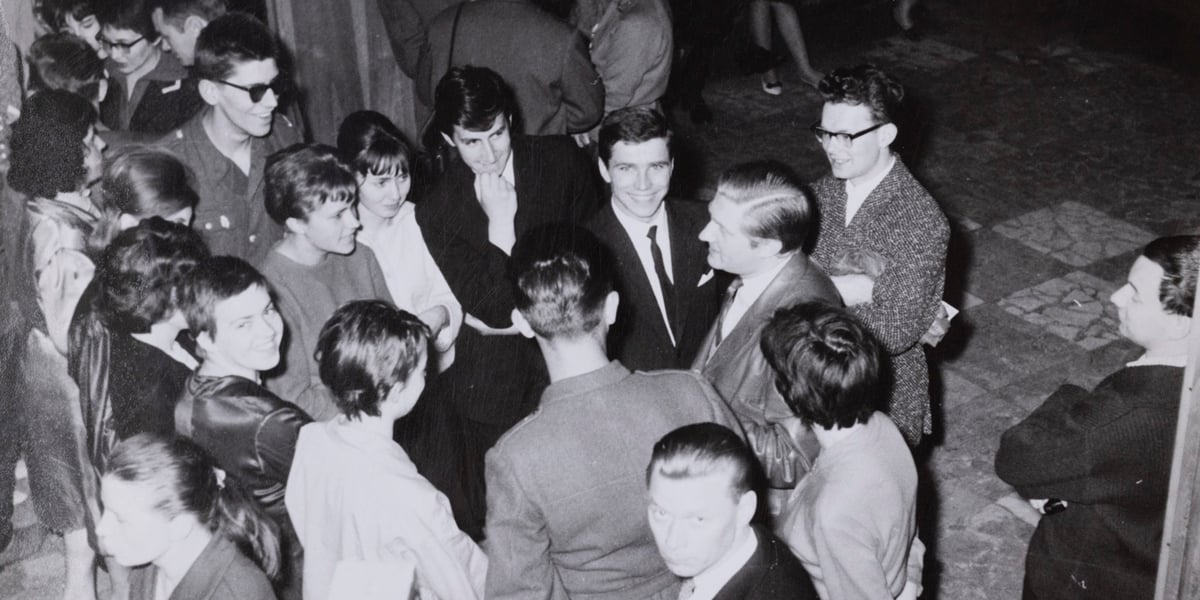 Na zdjęciu z lata 60. grupa młodych osób elegancko ubranych stoi wokół mężczyzny w średnim wieku. Aktor Igor Przegrodzki z uczestnikami konkursu recytatorskiego