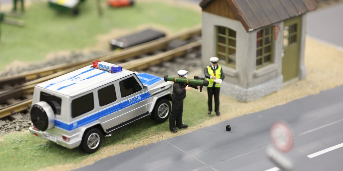 Na zdjęciu scenka z Kolejkowa: radiowóz i policjant z granatnikiem zamiast radaru