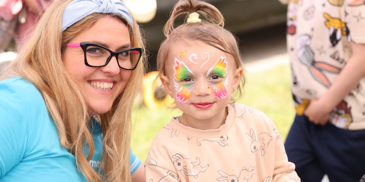 Uśmiechnięta blondynka i dziewczynka z pomalowaną twarzą na Dniu Otwartym MPK Wrocław