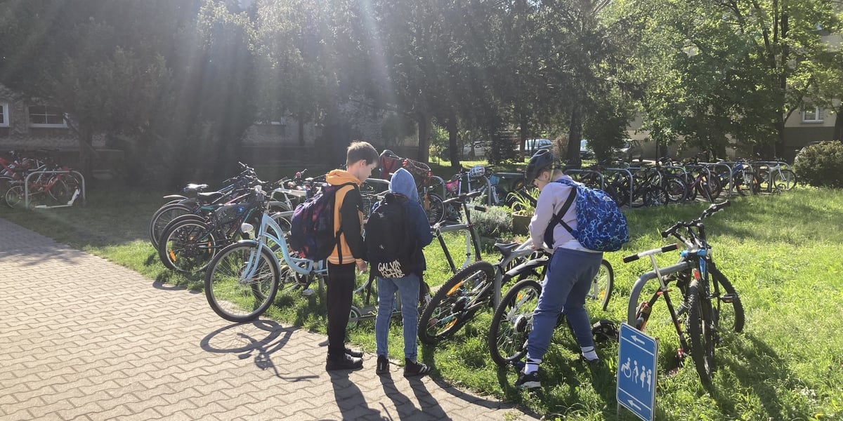 Trójka dzieci stoi przed rowerami zaparkowanymi pod szkołą