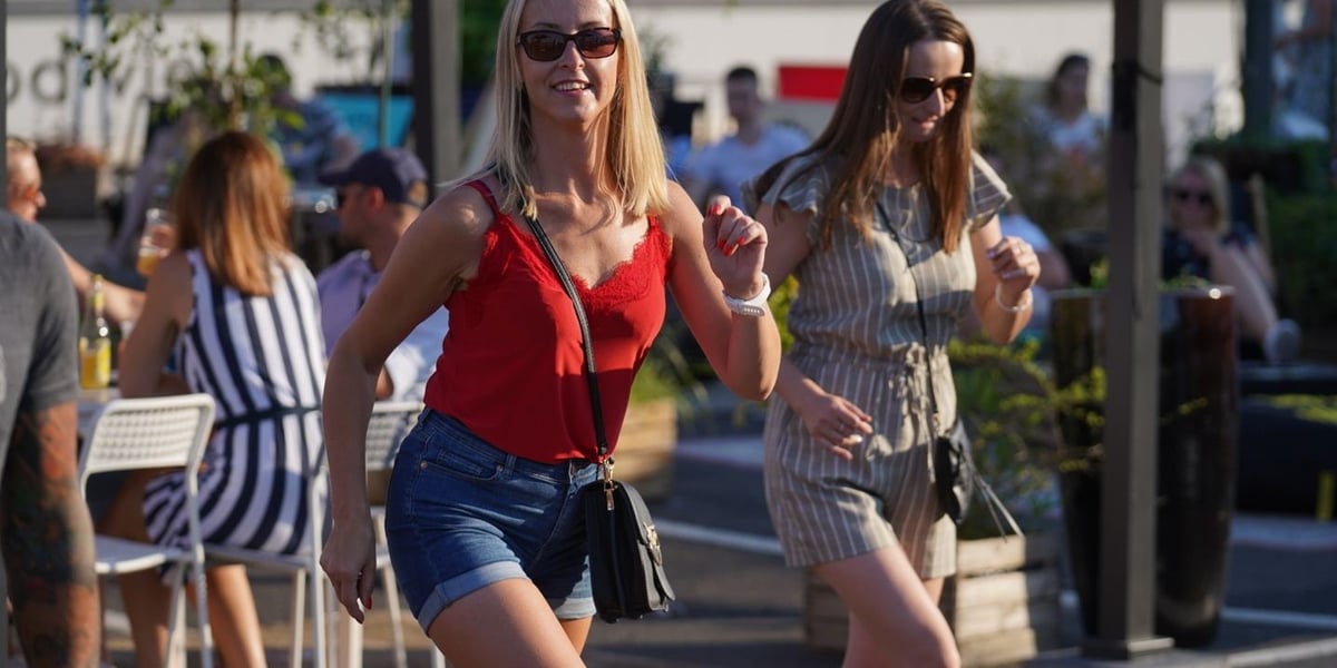 Dwie kobiety w tle więcej osób tańczą na dachu w Galerii Dominikańskiej.