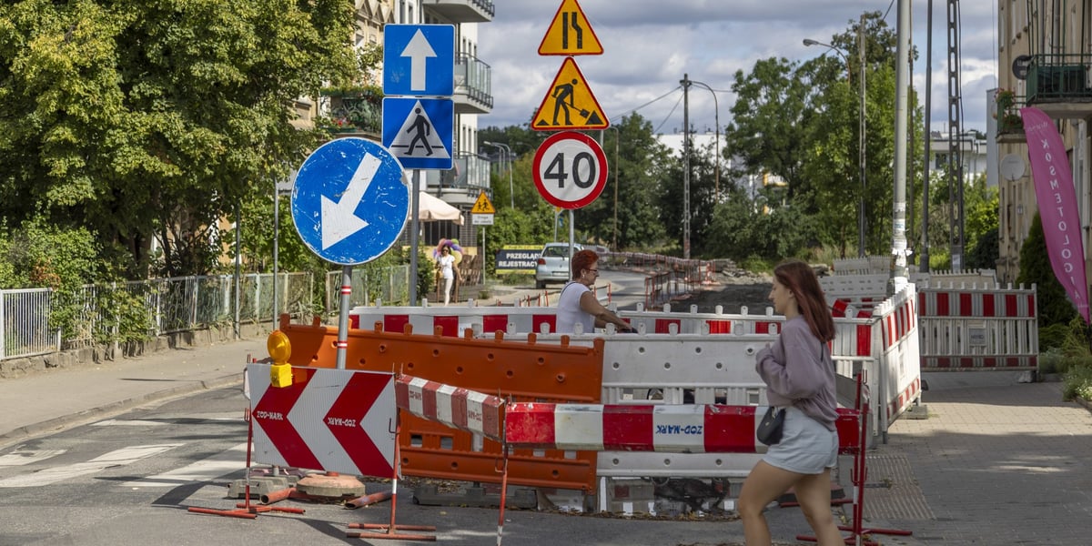 Dwie kobiety (w tle trzecia) koło znaków drogowych i biało-czerwonych osłon remontowych na ulicy Dolnobrzeskiej w Leśnicy