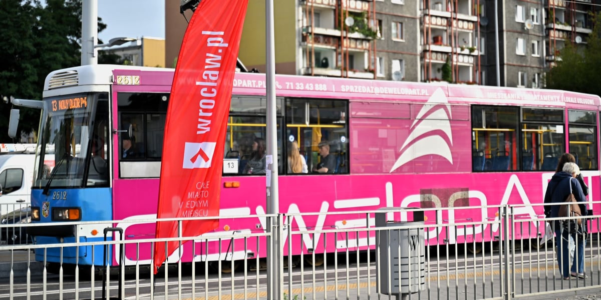 Tramwaj linii 13 jedzie na nowodworską pętlę. Na pierwszym planie chorągiewka wroclaw.pl sygnalizująca, że tu znajduje się punkt informacyjny o zmianach w komunikacji miejskiej.  