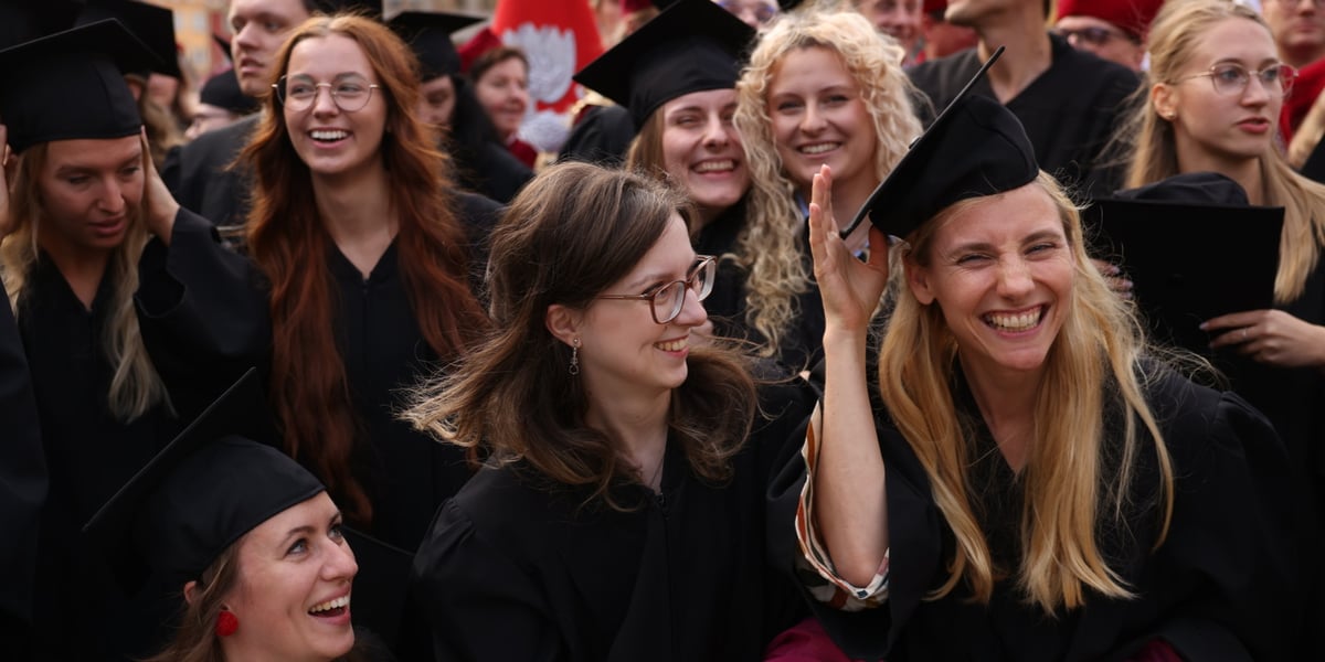 Gaudeamus w Rynku, 01.10.2023. Na zdjęciu uśmiechnięte kobiety i mężczyźni w akademickich strojach, zebrani na płycie wrocławskiego Rynku