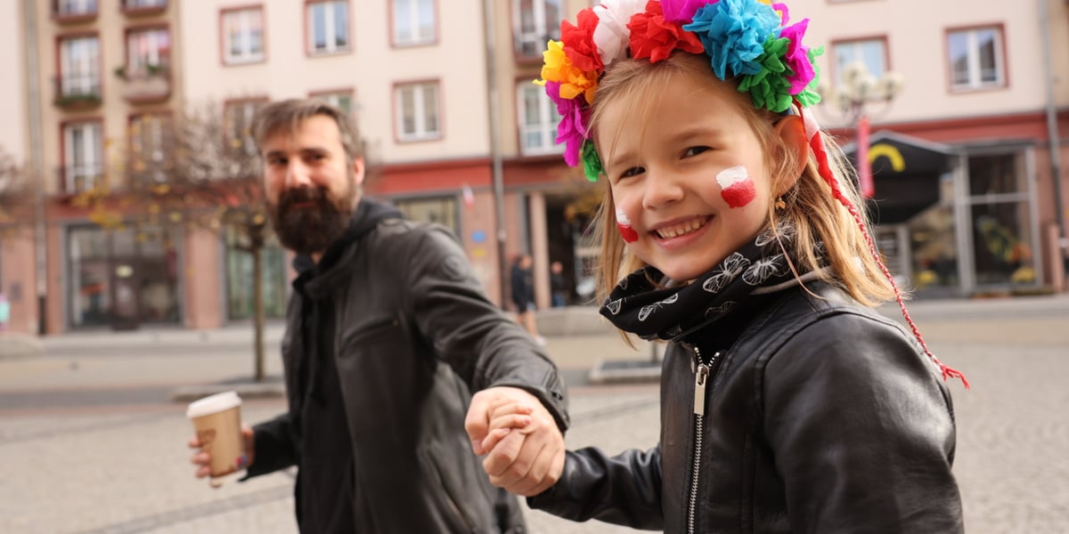 Uśmiechnięta dziewczynka z wiankiem trzymająca za rękę mężczyznę podczas WrocWalk 2023