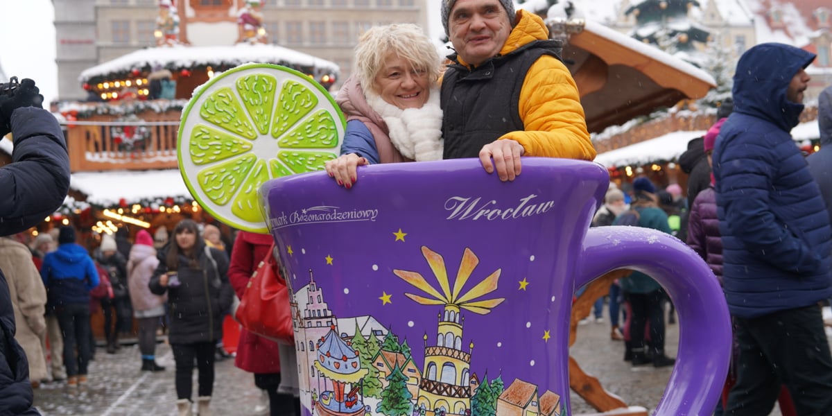 Jarmark Bożonarodzeniowy we Wrocławiu. Kobieta i mężczyzna pozują do zdjęcia w wielkim kubeczku buciku