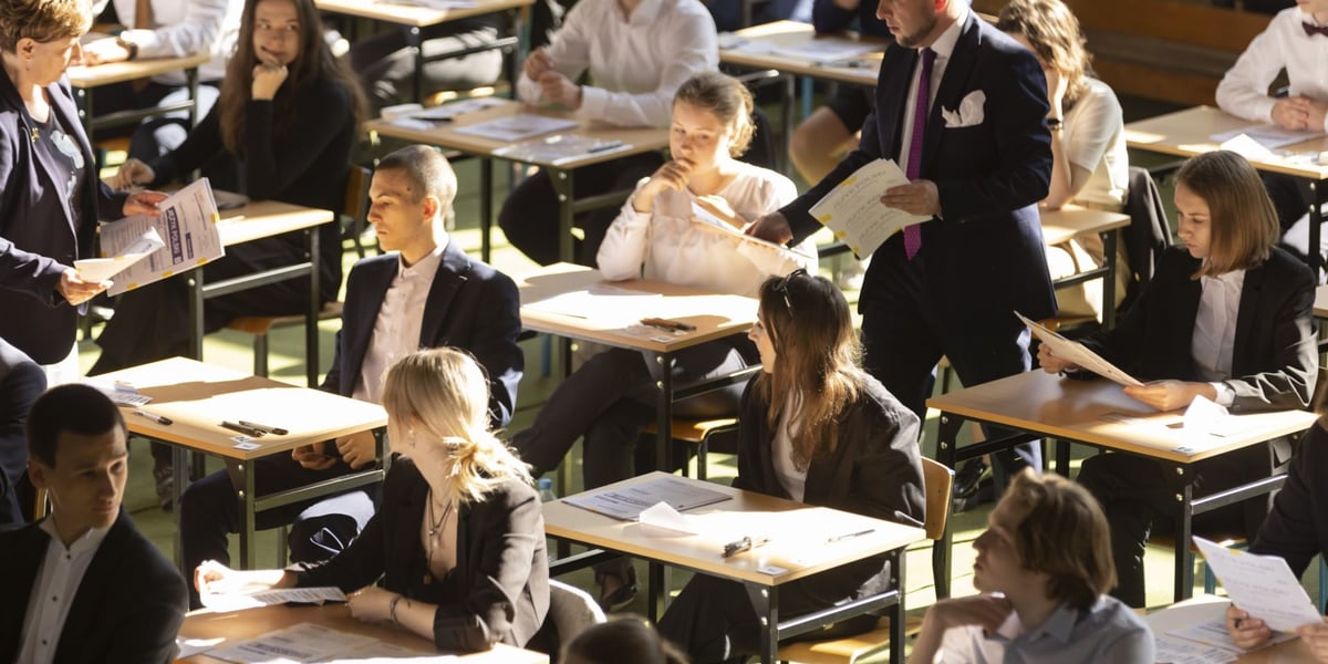 Uczniowie 7 LO we Wrocławiu podczas matury 2023. Siedzą w sali gimnastycznej przy stolikach