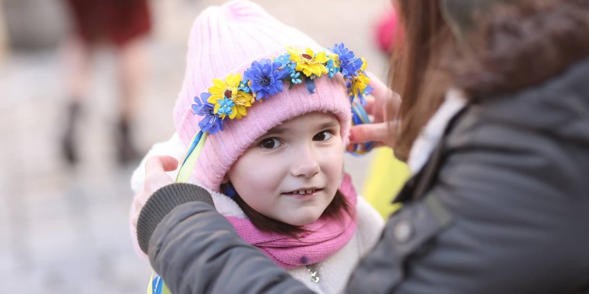 Dziewczynka w różowej czapce i wianuszku z niebieskich i żółtych kwiatów. Uroczystości związane z drugą rocznicą wybuchu wojny w Ukrainie (24 lutego 2024)