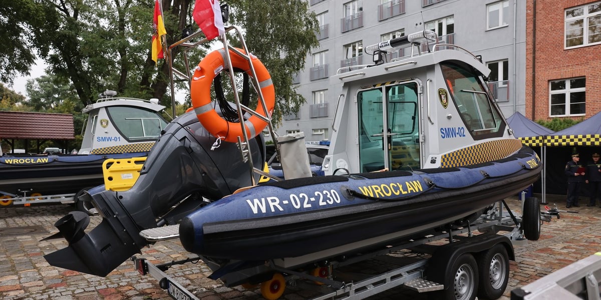 Łódź patrolowo-ratownicza na lawecie, na chodniku, w tle widać drugą łódź i budynek
