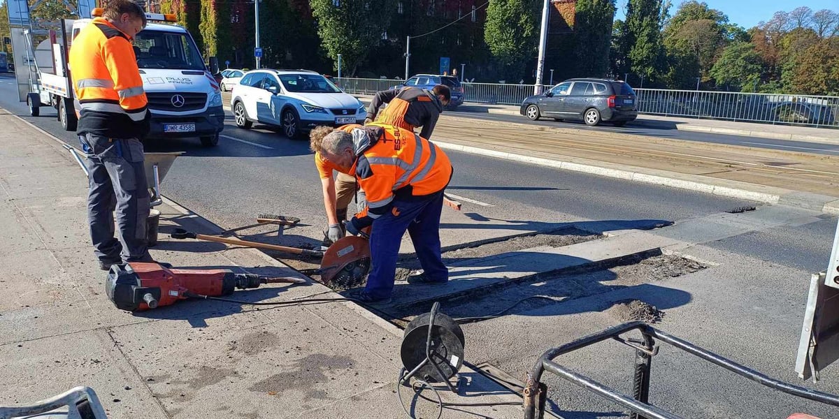 Trójka robotników w jaskrawych strojach podczas naprawy dylatacji na moście Pokoju (7 października)
