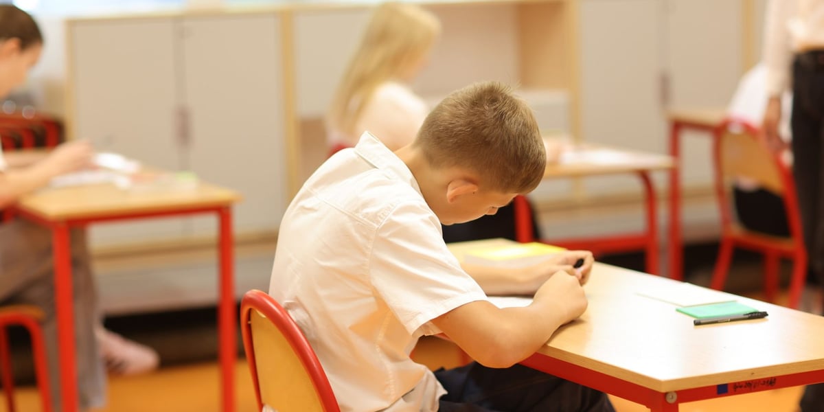 Uczeń siedzący w ławce podczas egzaminu ósmoklasisty w SP nr 29