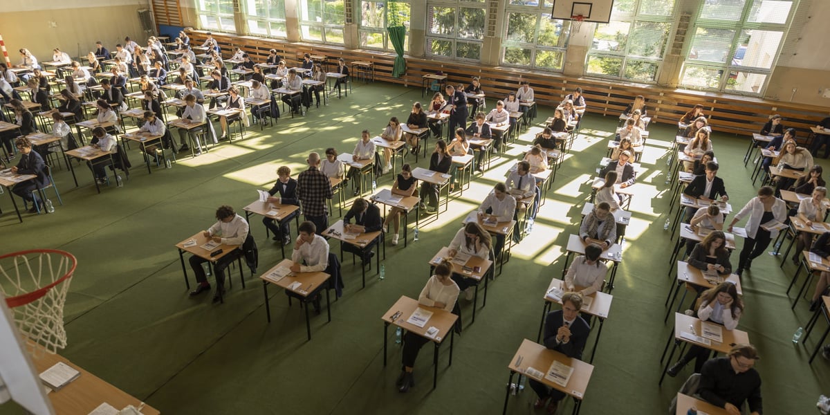 Matura w LO nr 7 we Wrocławiu. Uczniowie siedzą przy stolikach w sali gimnastycznej. Zdjęcie archiwalne