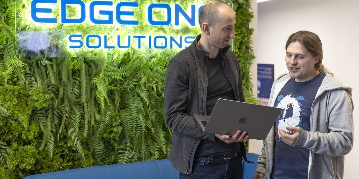 Dwóch mężczyzn z komputerem. Pracownicy Edge One Solutions  we Wrocławiu 