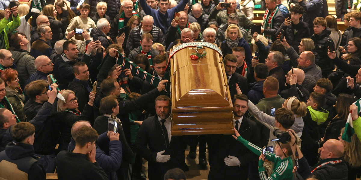 Pożegnanie trenera Jacka Magiery we Wrocławiu. Na zdjęciu grupa mężczyzn niesie drewnianą trumnę, otacza ich tłum ludzi, część w szalikach klubowych Śląska Wrocław