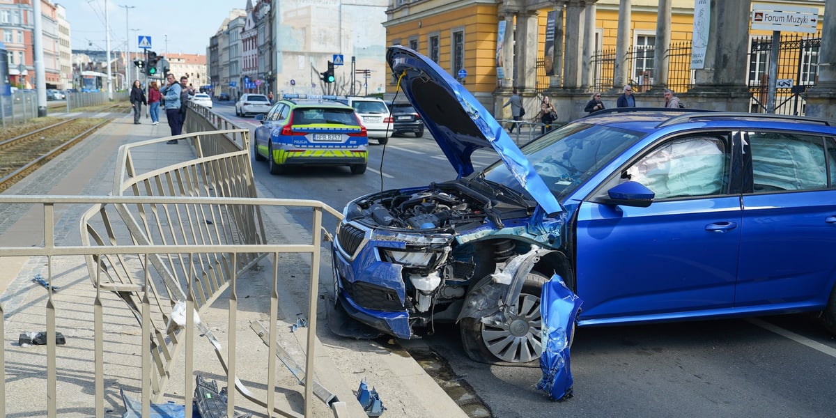 Rozbite auto stoi w poprzek ulicy Kazimierza Wielkiego przy uszkodzonych barierkach oddzielających przystanek tramwajowy.