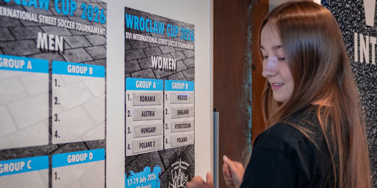 Dziewczyna przed tablicą z nazwami drużyn podczas losowania grup turnieju Wrocław Cup 2026