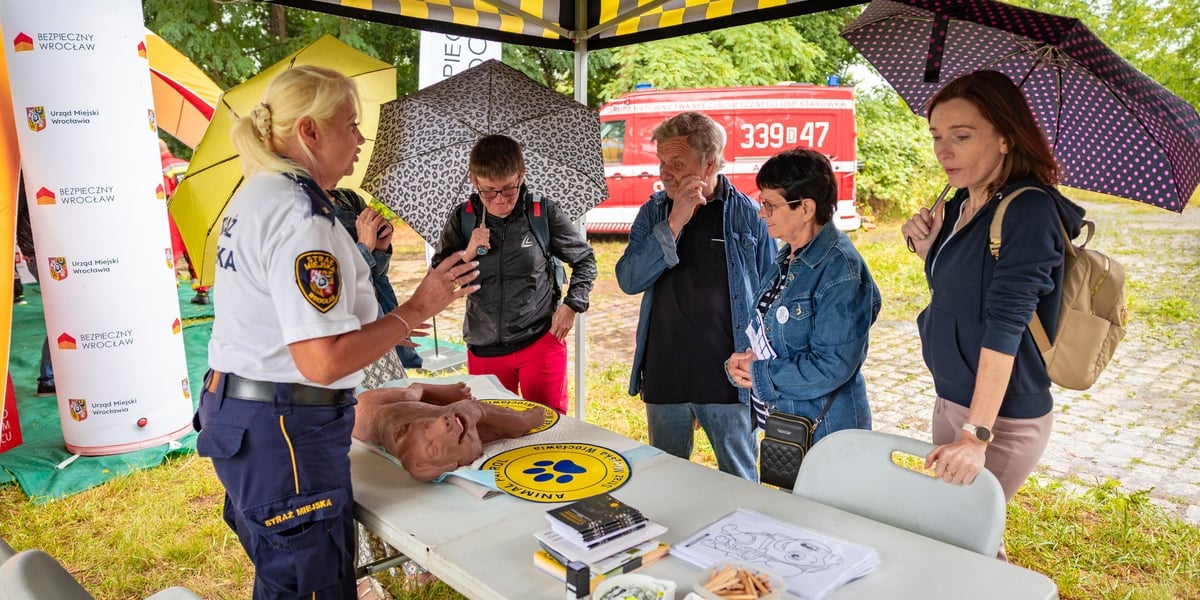 Piknik "Wakacje z Wroclaw.pl" pod wzgórzem Gajowym. Na zdjęciu stoisko Straży Miejskiej. Strażniczka rozmawia z kilkoma paniami