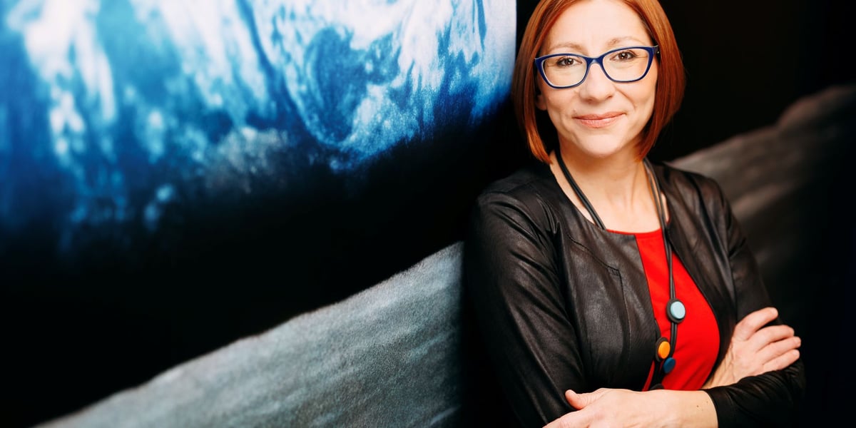 Kobieta stojąca przy zdjęciu Ziemi wykonanym z kosmosu - Anna Bukiewicz-Szul, koordynatorka programu ekranującego misji Ignis i współzałożycielka stowarzyszenia WroSpace.