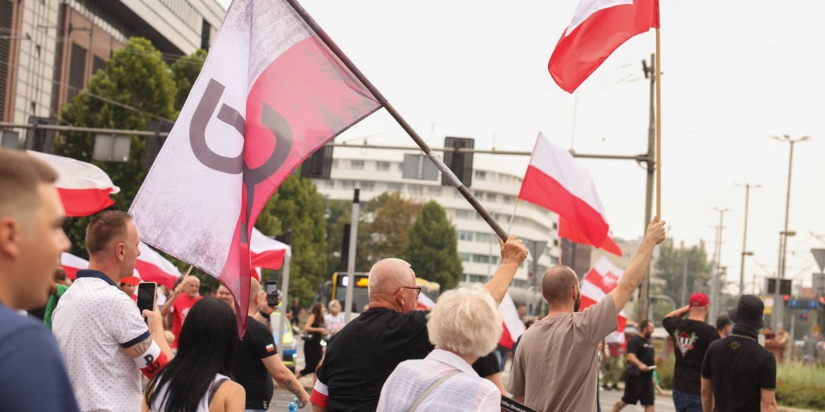 Grupa osób z biało-czerwonymi flagami na skrzyżowaniu ul. Oławskiej i Piotra Skargi w Godzinę "W"
