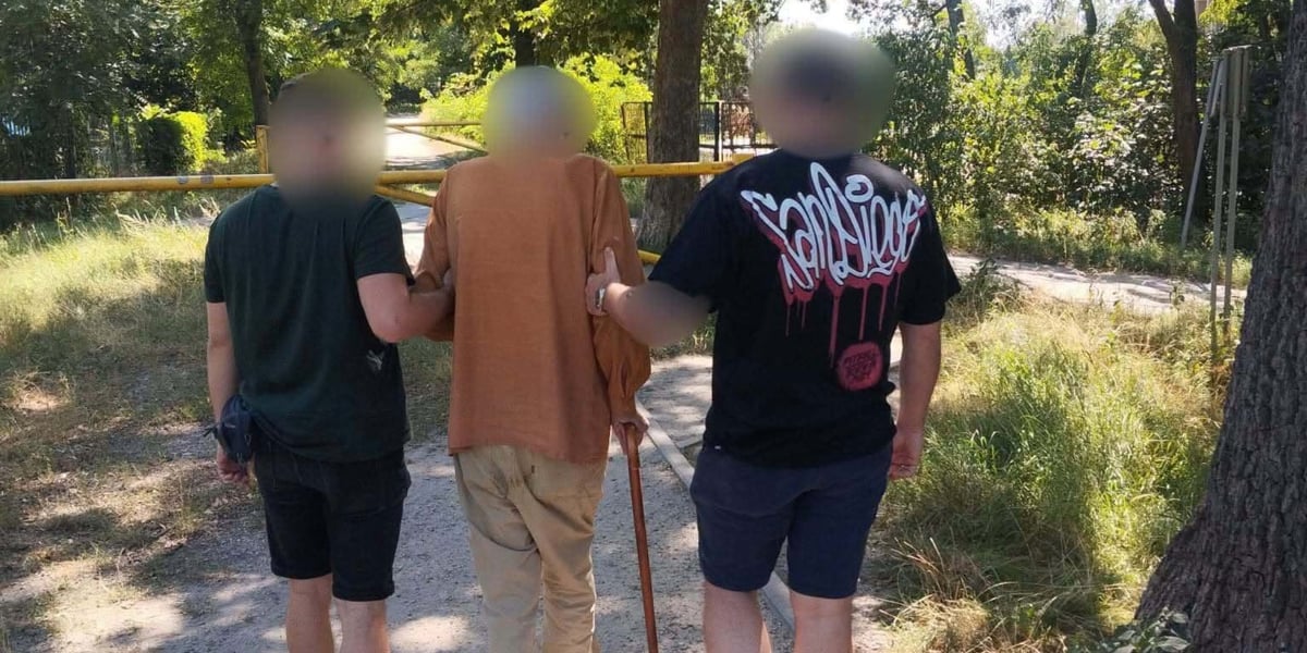 dwóch mężczyzn (policjanci w cywilnych ubraniach) prowadzi starszego mężczyznę