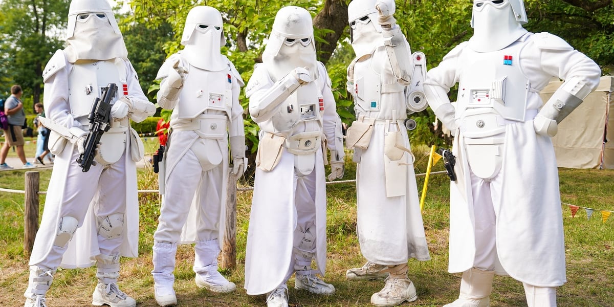 Pięć osób w białych kostiumach filmowych stoi na trawie w parku. Jeden trzyma czarny karabin. Dni Fantastyki 2026 we Wrocławiu