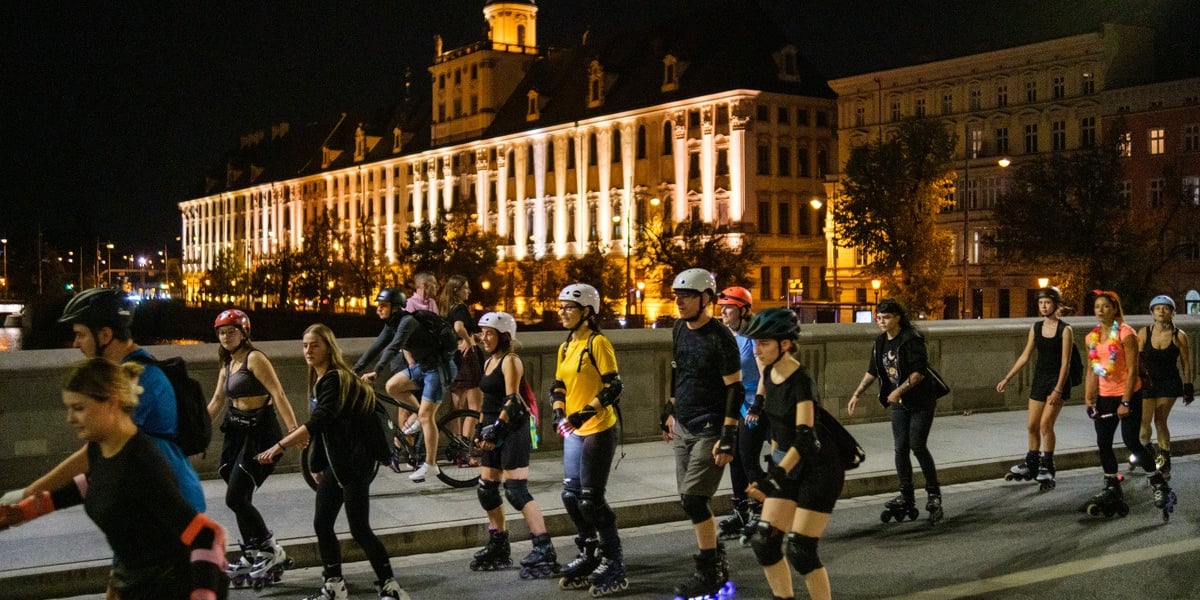 Nightskating 3 we Wrocławiu. Przejazd rolkarzy przez miasto. Na zdjęciu grupka na rolkarz, w tle oświetlony budynek Uniwersytetu Wrocławskiego