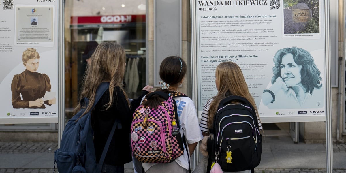 Trzy dziewczynki w wieku szkolnym oglądają wystawę "Kroniki Wrocławianek" na ulicy Oławskiej
