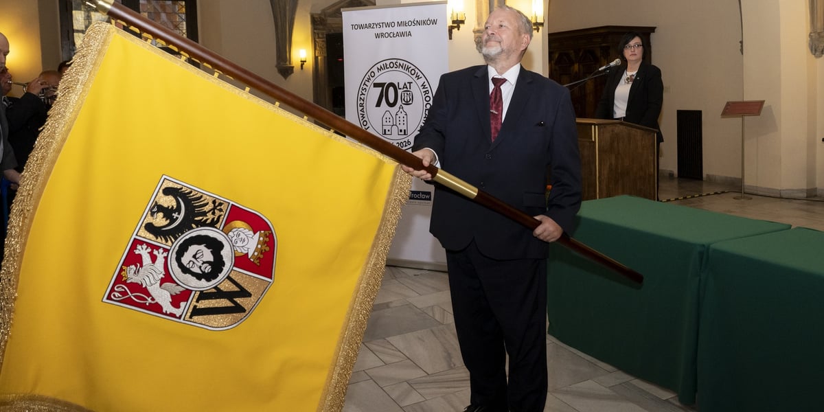 Mężczyzna w garniturze trzymający sztandar z herbem Wrocławia - Towarzystwo Miłośników Wrocławia odbiera własny sztandar podczas uroczystości z okazji 70-lecia istnienia, 23 września 2026 r.