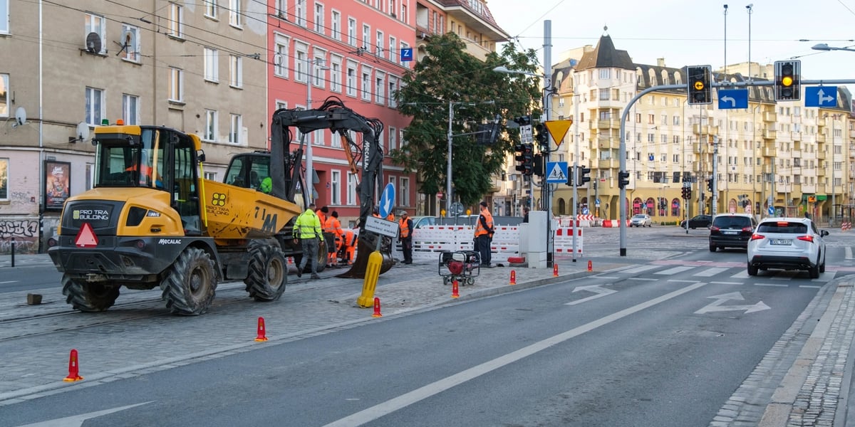 zdjęcie z remontu kostki w ul. Pomorskiej: żółta maszyna budowlana i rozpoczynający remont pracownicy w strojach roboczych