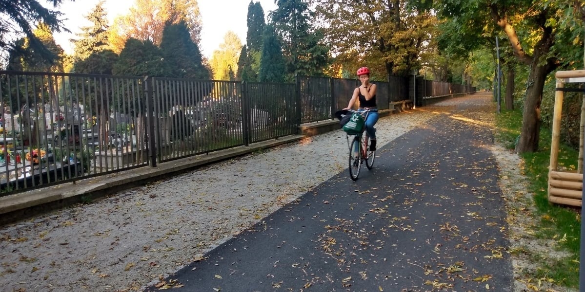 Na zdjęciu istniejący odcinek Promenady Krzyckiej, wzdłuż ogrodzenia cmentarza Ducha Świętego przy ul. Bardzkiej. Do końca roku powstanie jego przedłużenie w kierunku ul. Ziębickiej.  Na trasie kobieta w czarnym podkoszulku jedzie na rowerze.