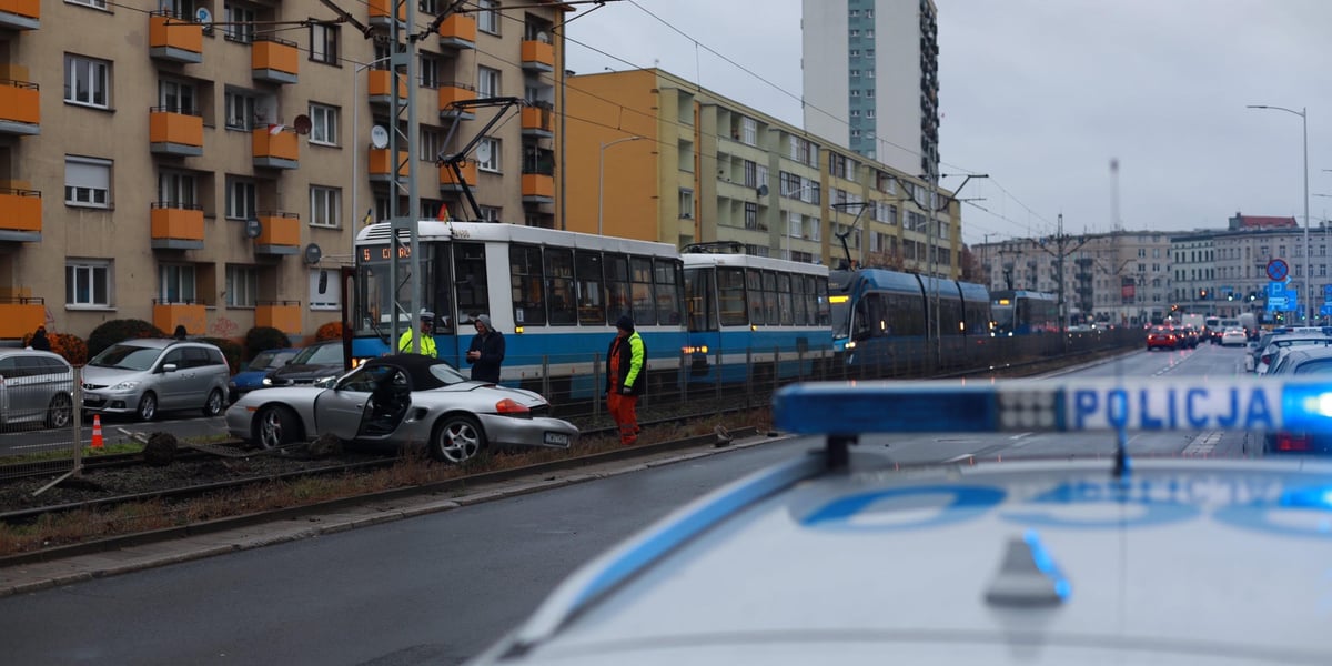 na zdjęciu samochód na torowisku blokuje przejazd tramwajów, na pierwszym planie radiowóz policyjny, w tle "korek" tramwajów