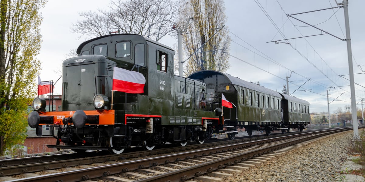 Na zdjęciu widać zabytkowy pociąg - lokomotywa i dwa wagony - który jedzie po torach