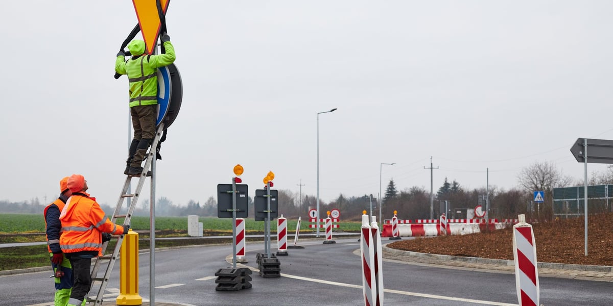 Na zdjęciu: robotnicy odsłaniający znak drogowy na nowym rondzie w ulicy Grota-Roweckiego