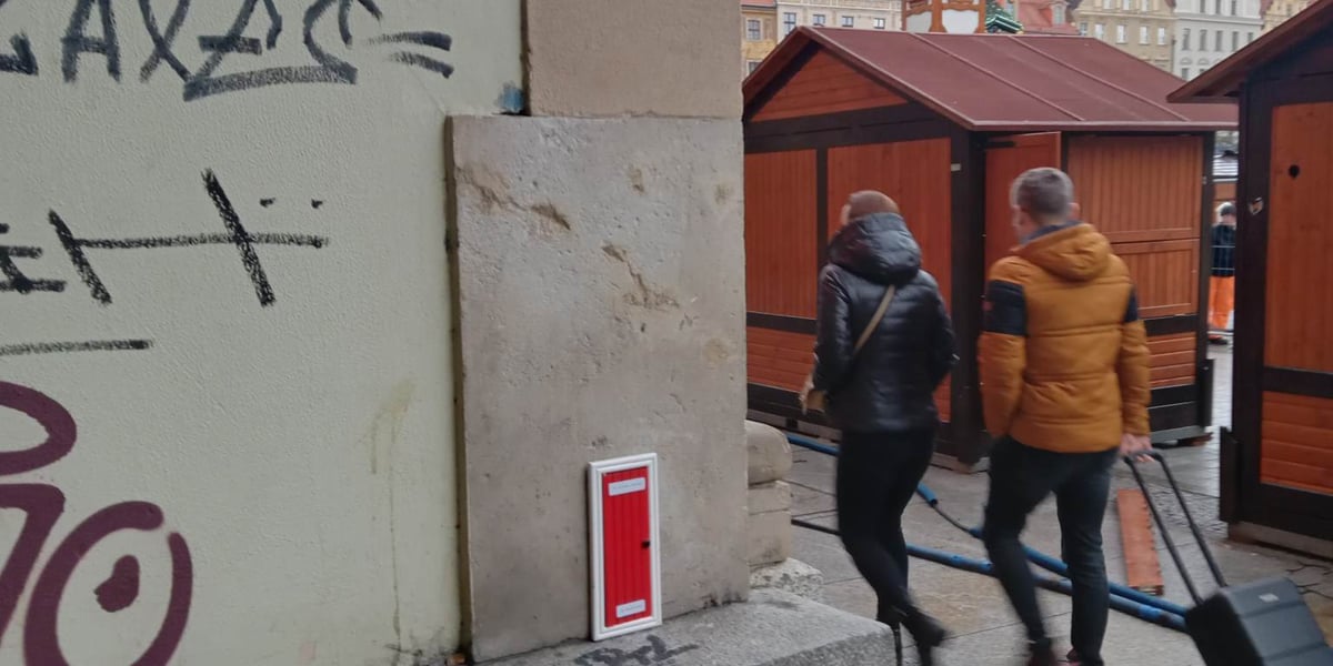 Na zdjęciu widać czerwone drzwiczki, które można zobaczyć (i otworzyć) na wrocławskim Rynku. Są zamontowane na ścianie, w przejściu pod jedną z kamienic w południowej części Rynku