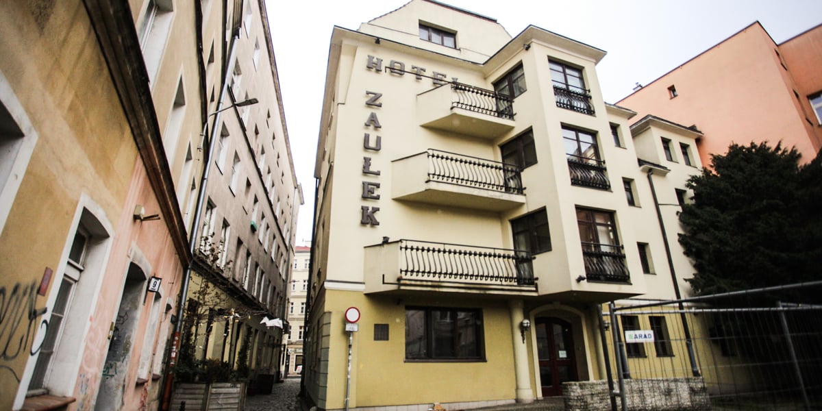 Na zdjęciu kilkupiętrowy budynek ze spadzistym dachem z napisem na elewacji hotel Zaułek