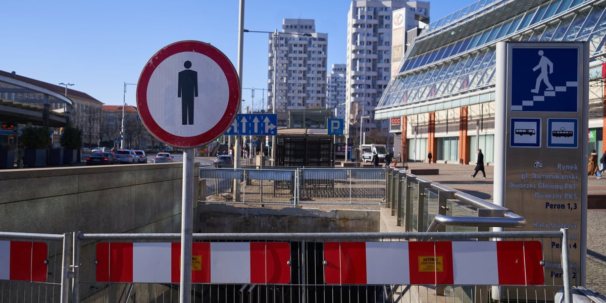 Barierki i znak przed zamkniętym zejściem do przejścia podziemnego przy Pasażu Grunwaldzkim. Zdjęcie zrobione w lutym 2023 r.