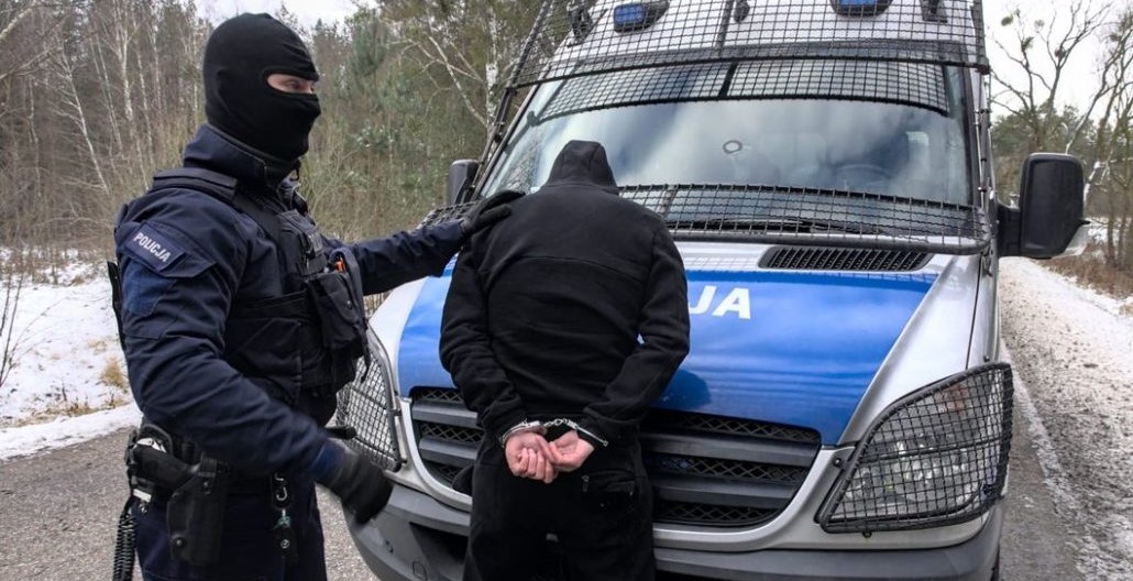 Na zdjęciu widać policjanta w mundurze i zatrzymanego mężczyznę