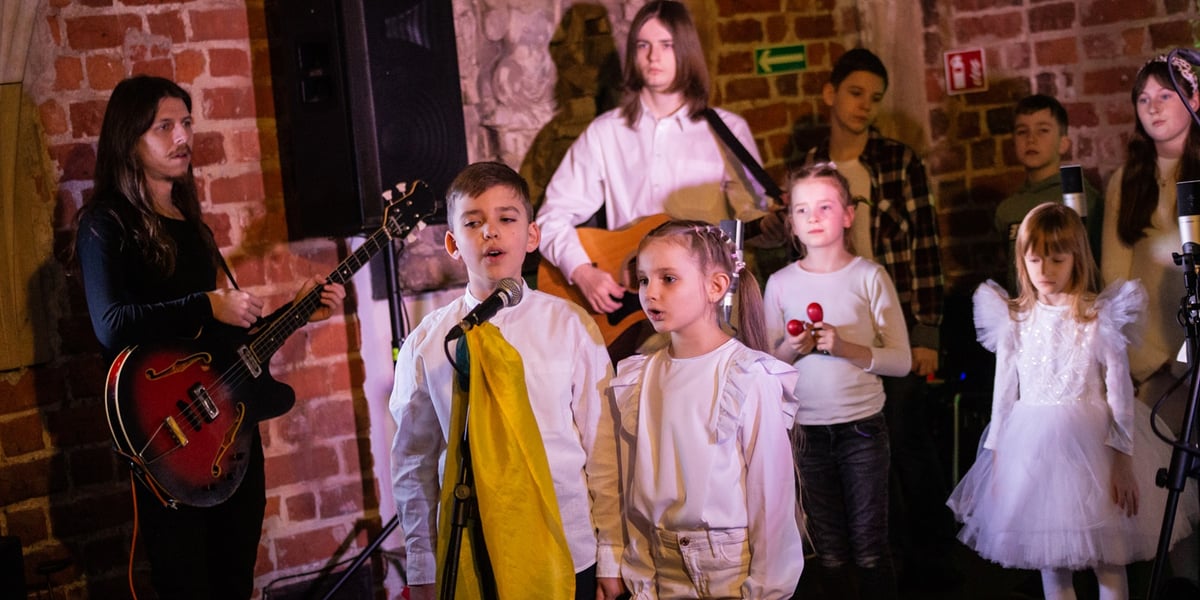 Na zdjęciu koncert zespołu KapustaBand w Muzeum Architektury we Wrocławiu. Na zdjęciu widać chłopca i dziewczynkę stojących i śpiewających przed mikrofonem