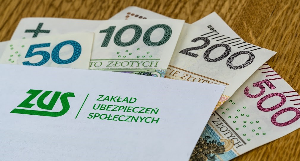 Na zdjęciu widać banknoty i kopertę z napisem ZUS