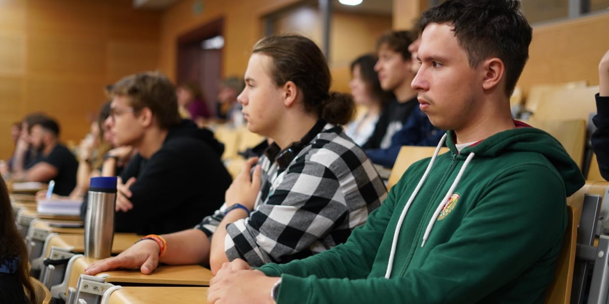 Trzej chłopcy w wieku licealnym, którzy siedzą na sali wykładowej podczas II Forum ds. Uzależnień