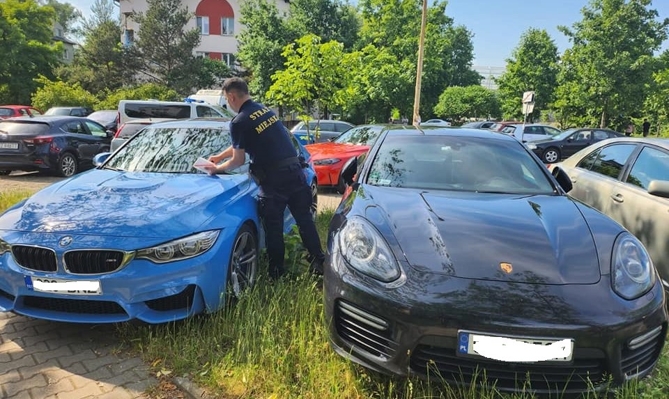 Źle zaparkowane samochody. Strażnik miejski zostawia informację o mandacie