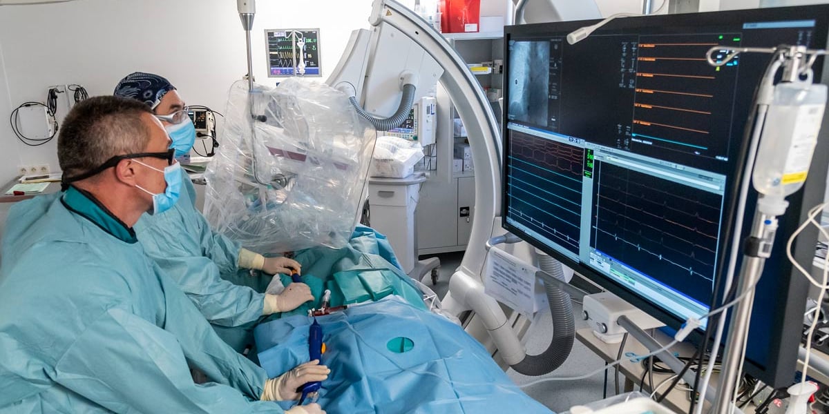 Sala operacyjna, dwóch lekarzy - dr Krzysztof Nowak, kierownik Pracowni Elektrofizjologii Inwazyjnej Instytutu Chorób Serca USK we Wrocławiu, i dr Stanisław Tubek z Pracowni Elektrofizjologii Inwazyjnej Instytutu Chorób Serca USK we Wrocławiu - w środku leży okryty pacjent, a po prawej monitory